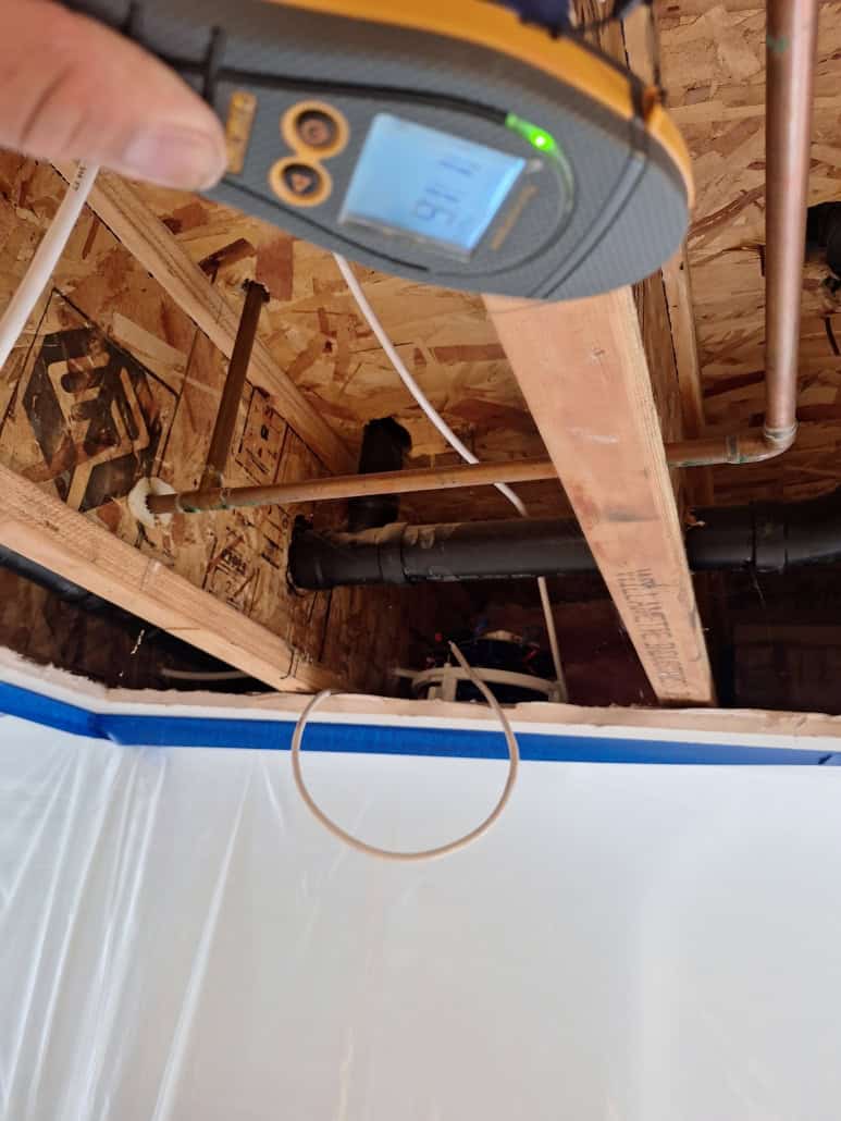 Technician using moisture readings to verify drying after an AC leak
